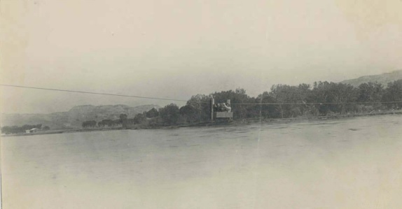 View of three men in a hand-pulled passenger ferry crossing the Missouri River, Judith Landing, near Winifred, MT.
