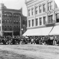 Early automobile touring group posed on Higgins Avenue in front of the Florence Hotel, Missoula, Montana.